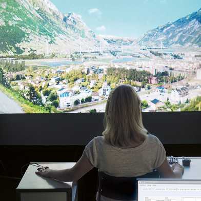 Eine Frau sitzt im Virtual Reality Lab mit Landschaftsbildern