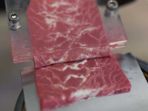Ein tranchiertes, pflanzliches Steak liegt auf einer Plexiglasplatte