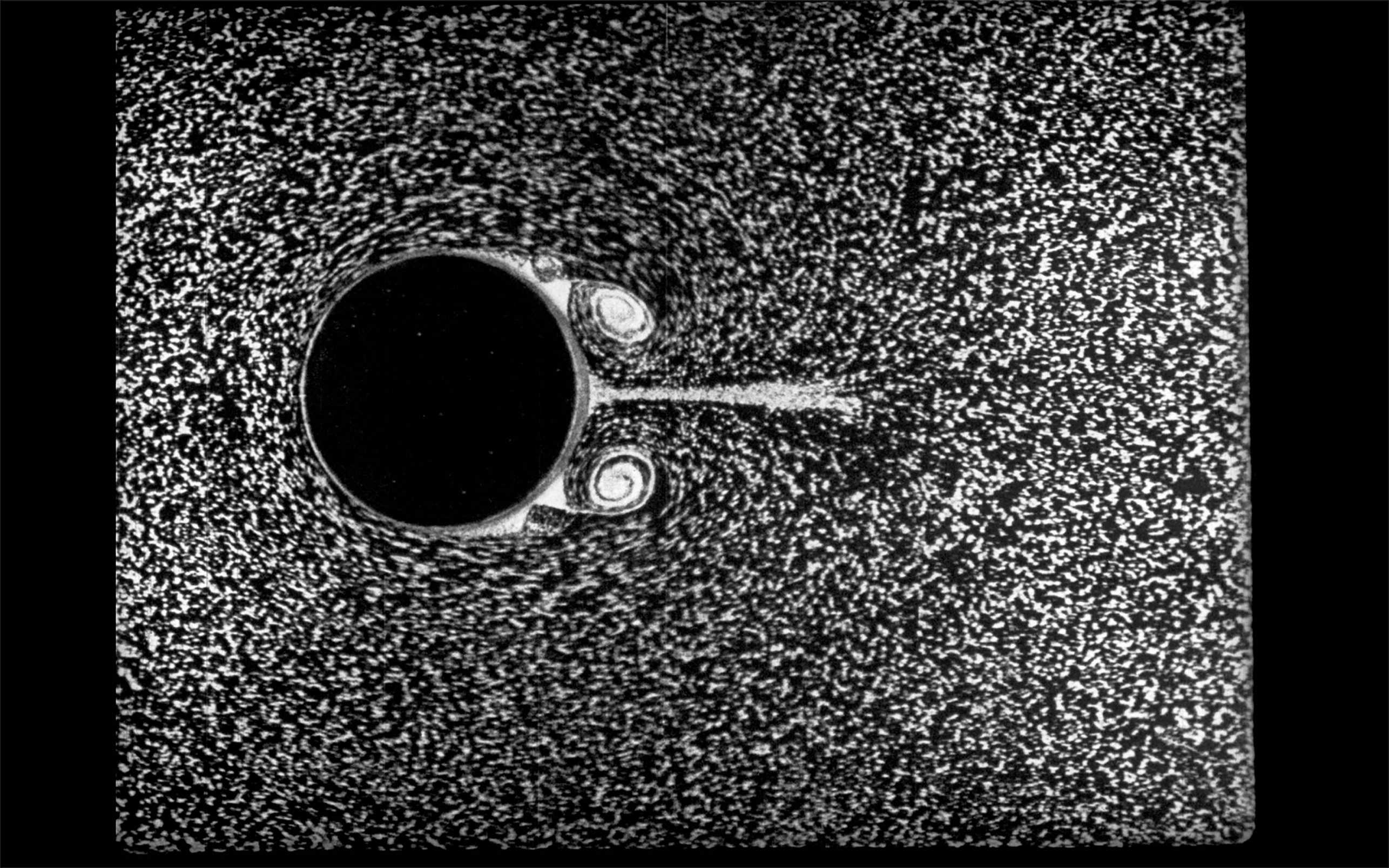 Schwarz-weisses Bild mit weissen flimmernden Partikeln und einem schwarzen Kreis