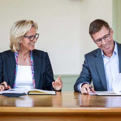 Sabine Keller-Busse und Joël Mesot unterschreiben lächelnd einen Vertrag