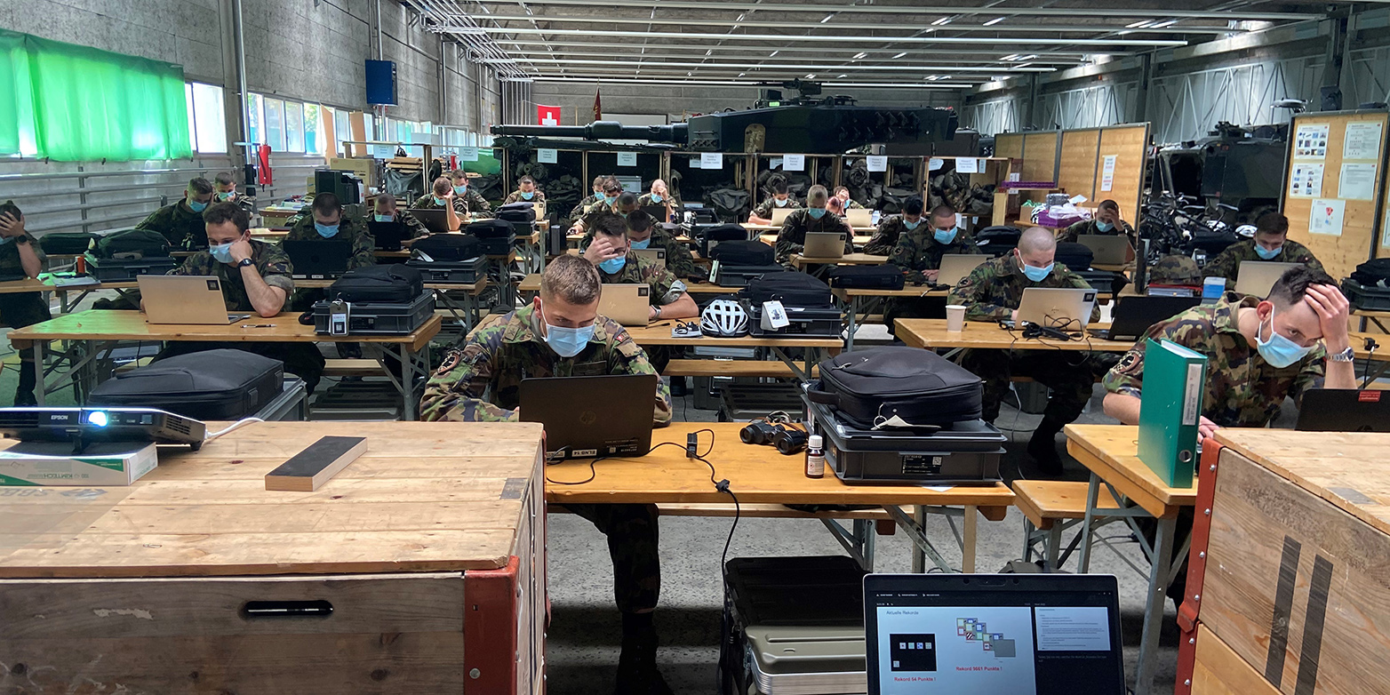 Offiziere der Schweizer Armee arbeiten an Laptops in einer Halle