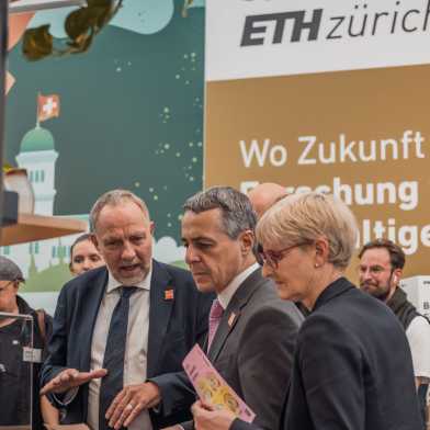 Detlef Günther (links) steht mit Ignazio Cassis und einer weiteren Frau vor dem "Start-up-Turm" des ETH-Standes und spricht. 