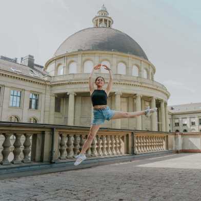 Frau macht eine Balletfigur vor dem Hauptgebäude der ETH Zürich