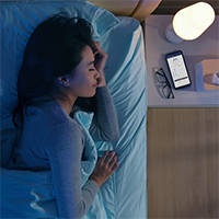 schlafende Frau mit Smartphone und App auf dem Nachttisch