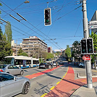 Strassenkreuzung mit Bus, Autos, Velofahrern und Ampeln